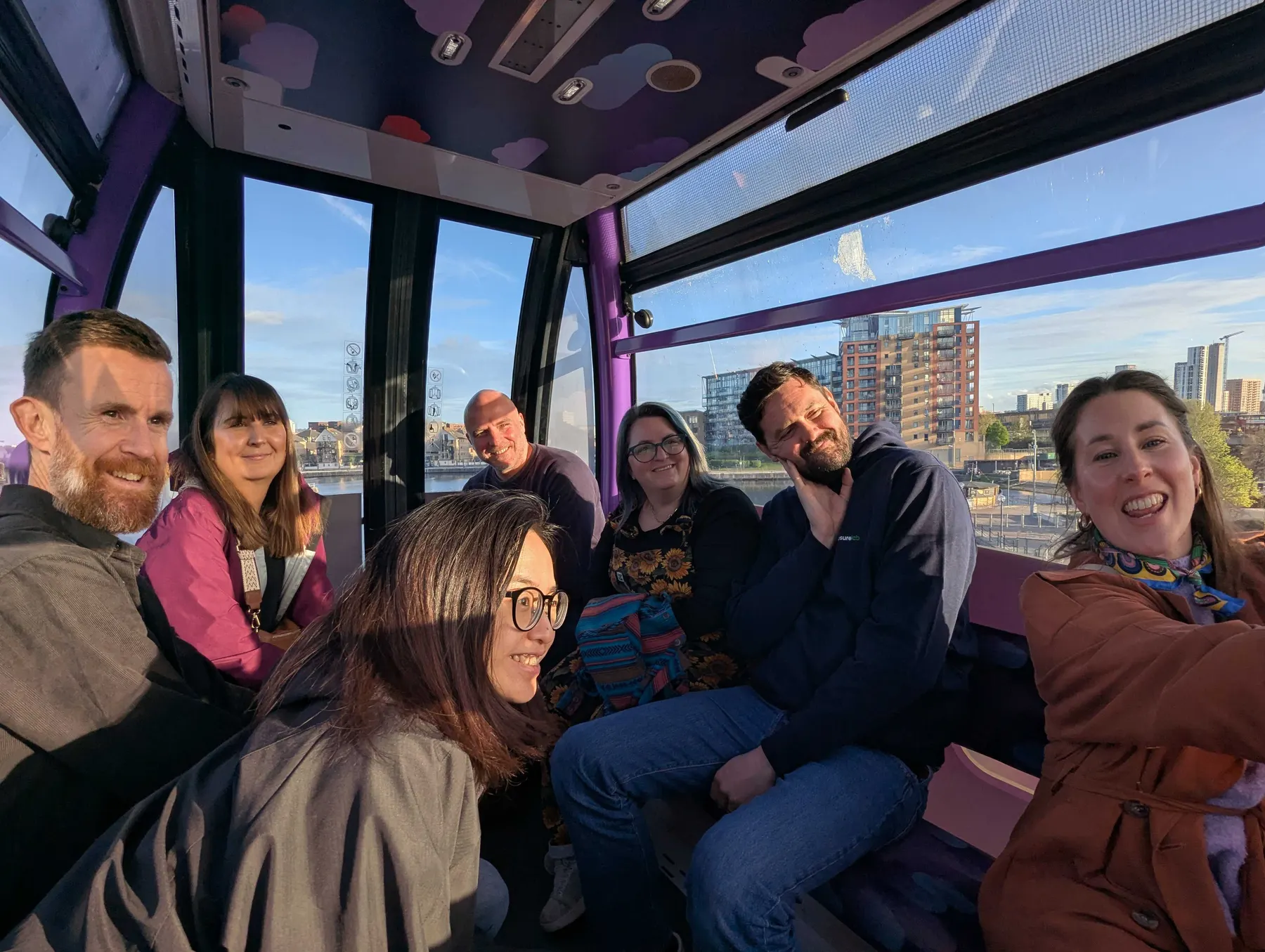 Measurelab colleagues smiling in a cable car cabin above the Thames