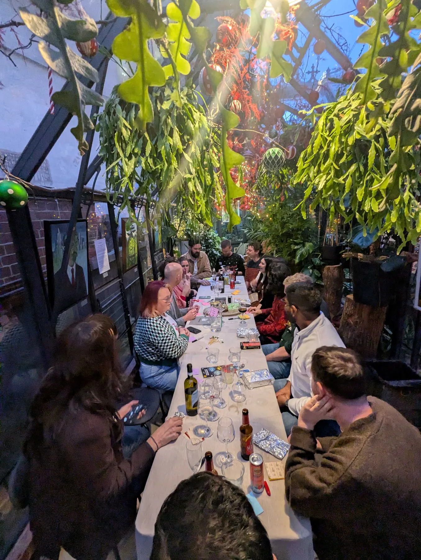 The team at a long table in a glasshouse restaurant at the Christmas party