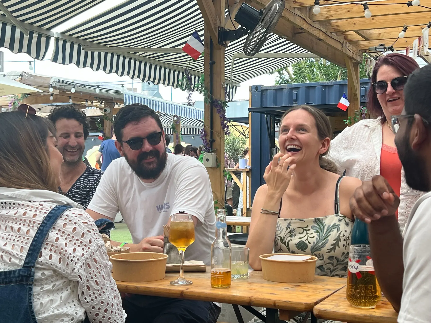 Colleagues laughing round an outdoor table at the summer social